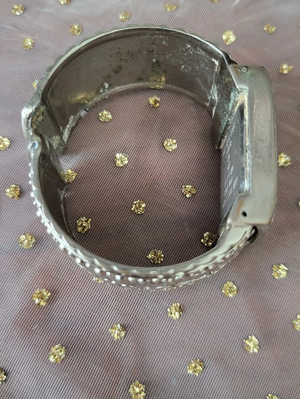Silver bracelet watch with ornate scrollwork design has antique white face